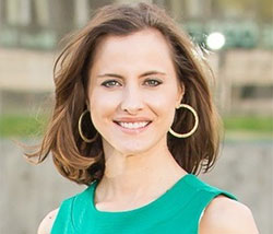 A woman in a green dress with gold hoop earrings.